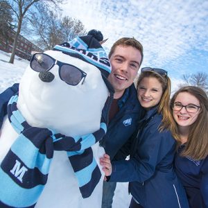 3 students with snowman in UMaine hat and scarf