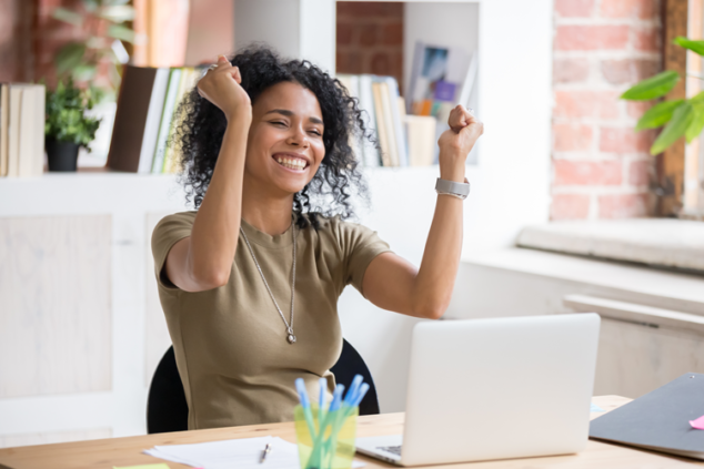 person at laptop with their hands up in excitement
