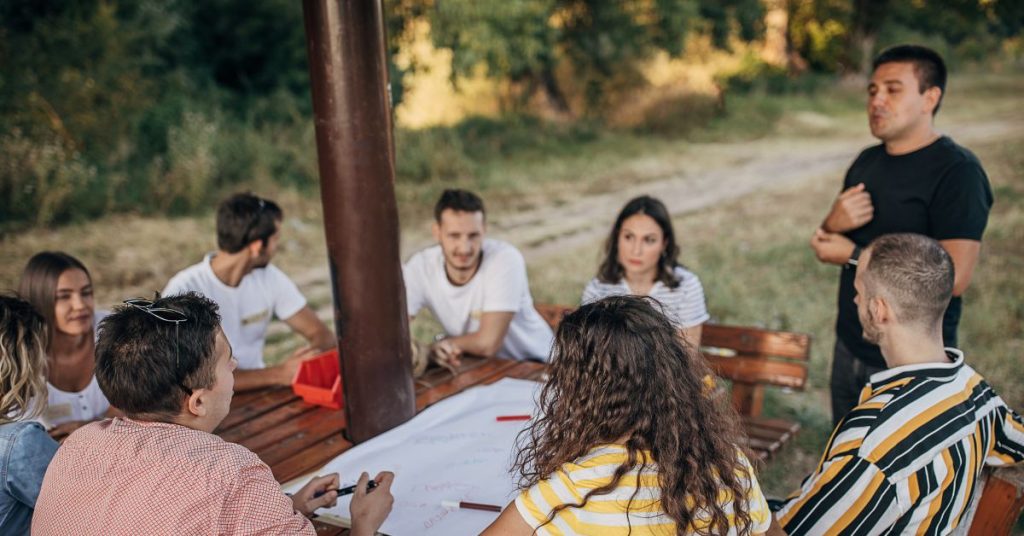 Person standing speaking to a group sitting outside