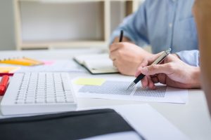 Tutor books with friends, person sitting pointing studying together at desk with classmates exams, hands with books or textbooks writing to notebooks, learning, education and school concept