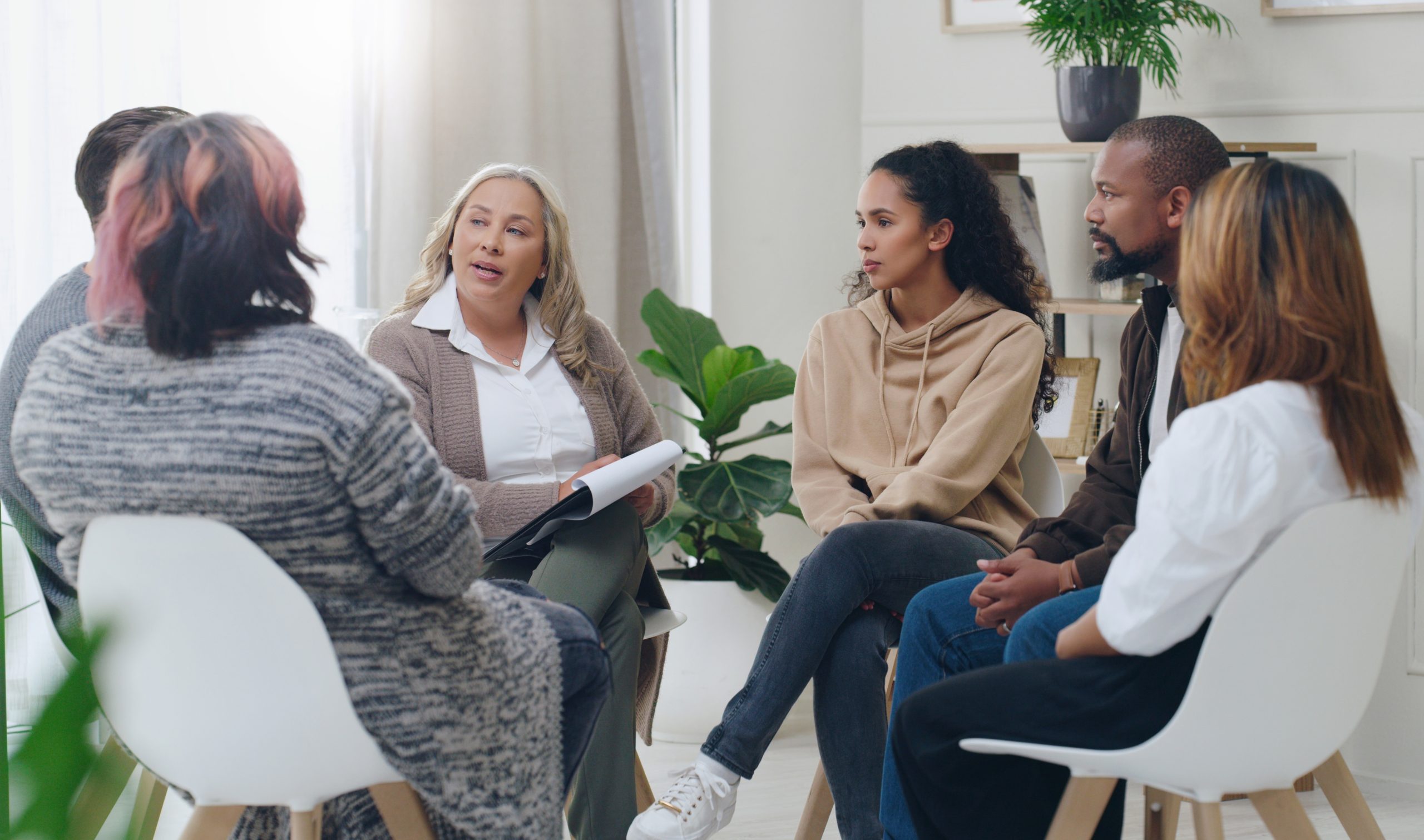 A group of people sitting in a circle listening to the group leader