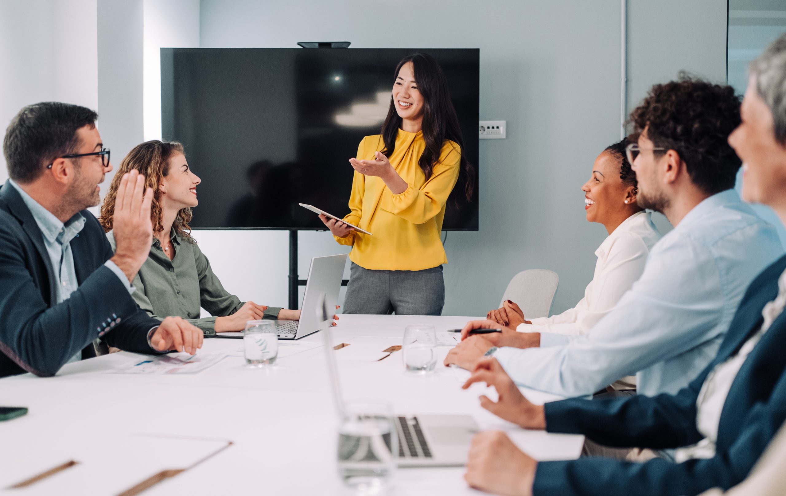 A person leading a meeting and gesturing to an attendee
